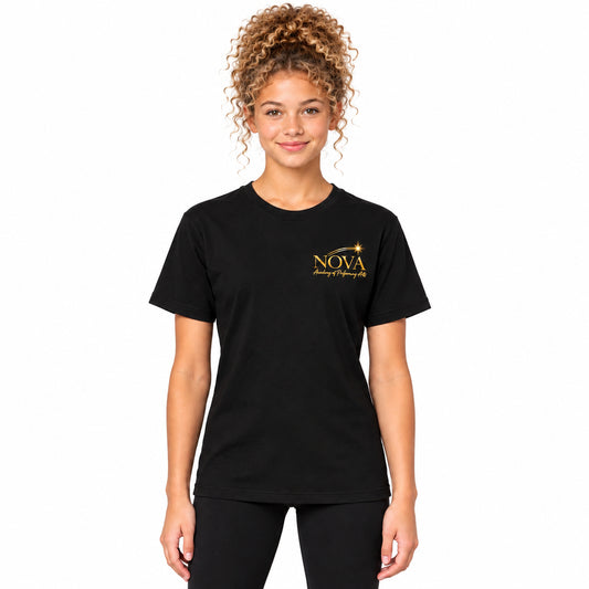 A woman with curly light brown hair wearing a black short-sleeve crewneck t-shirt with a gold 'NOVA Dance of Fireworks 2025' logo on the left chest, paired with black leggings, against a solid light gray studio background.