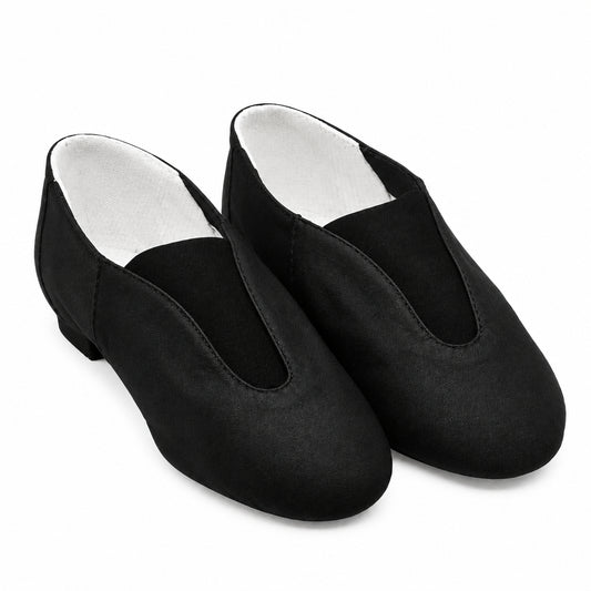A pair of black slip-on dance shoes with a satin-like finish, displayed on a beige background.